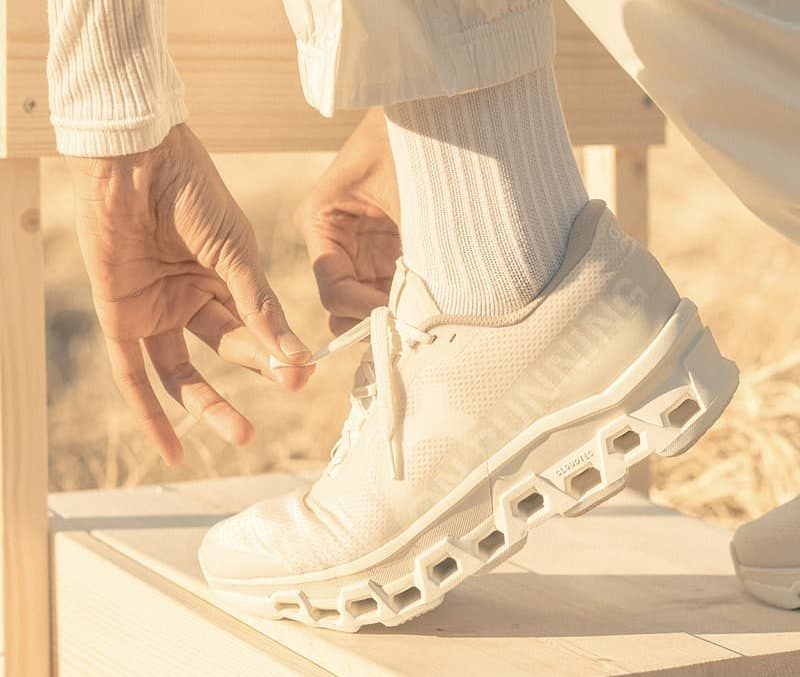 man tying On INVINCIBLE shoe in grass on chair