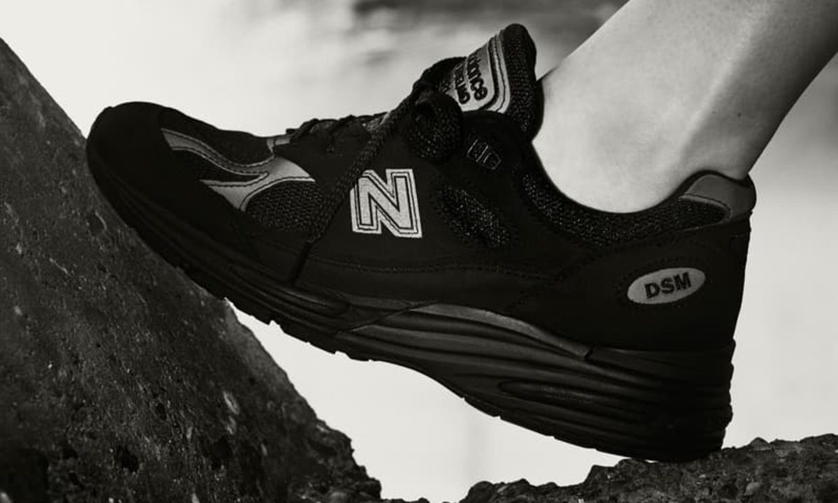 model in black new balance standing on rock
