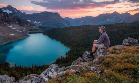 A man hiking to a beautiful view of a lake at sunset