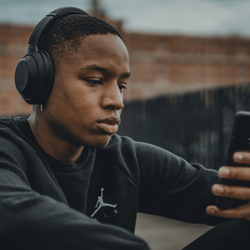 Man with headphones on looking at his phone