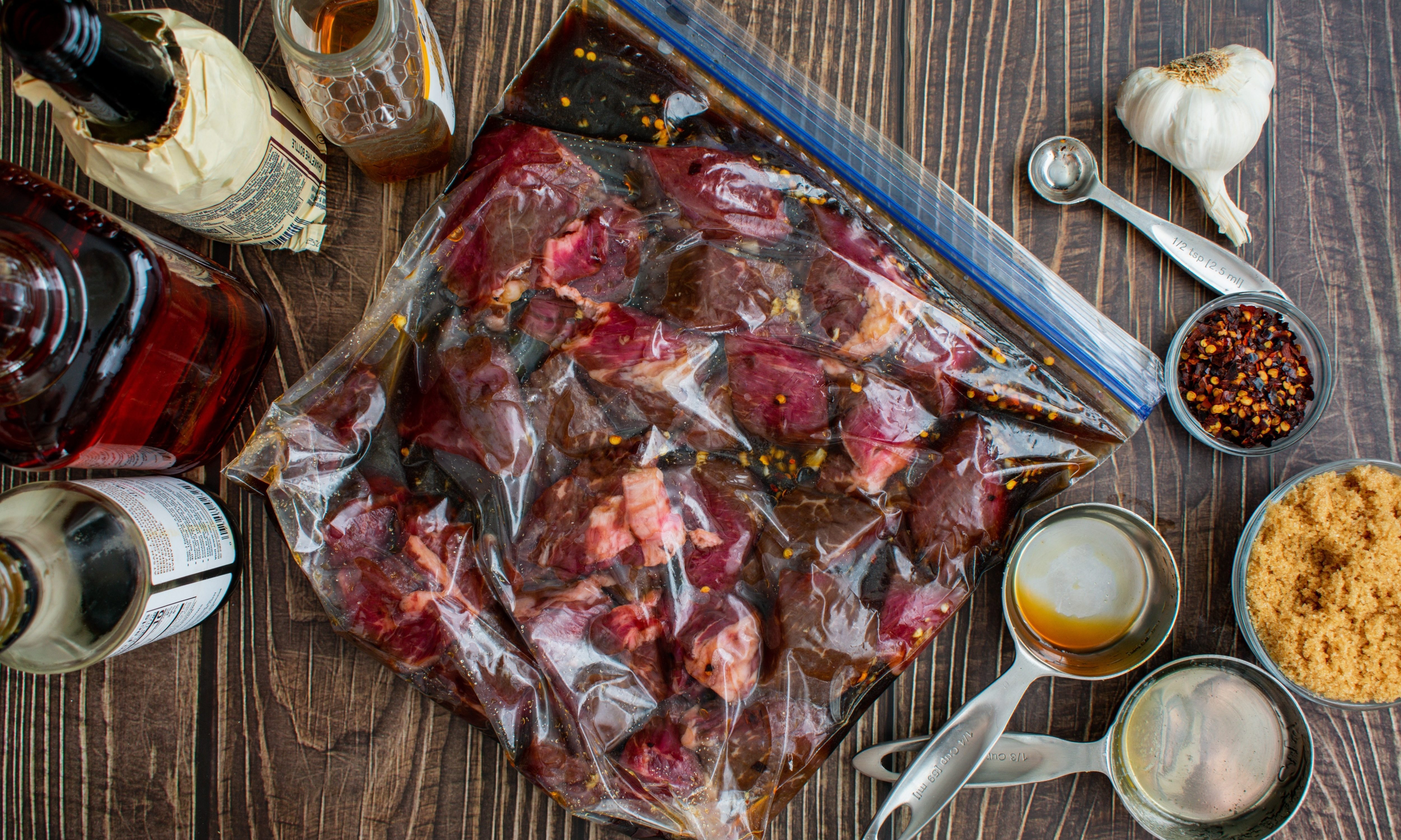 Marinating Raw Steak Tips in a Plastic Ziplock Bag: Uncooked beef tips in a plastic bag surrounded by marinade ingredients