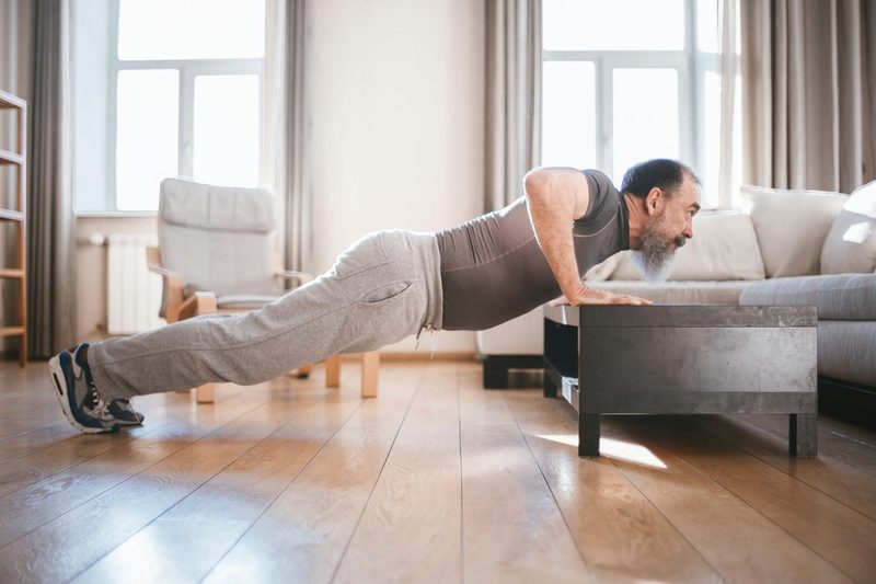 man exercising older man doing push ups workout inside home
