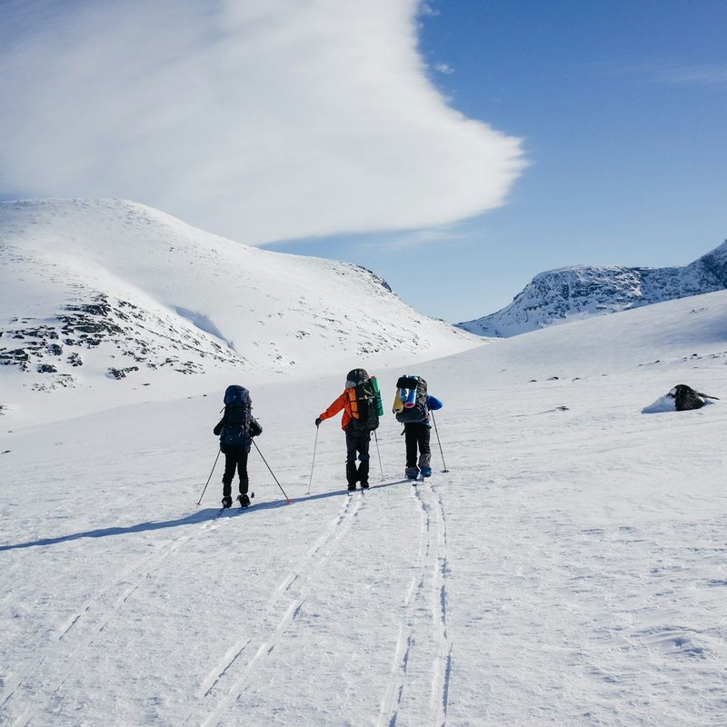 Three people cross-country skiing on a snowy mountain top