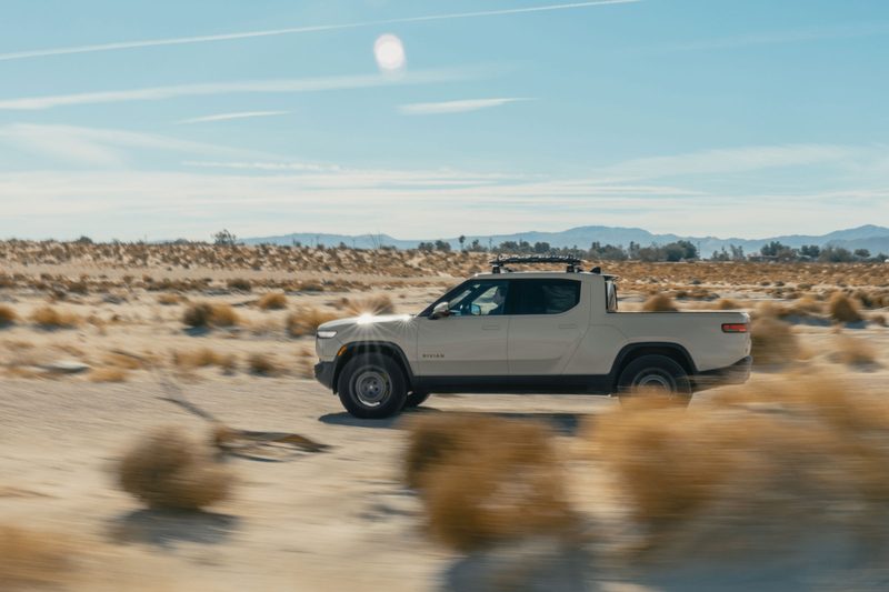 Rivian R1T California Dune Edition driving on a remote desert road.