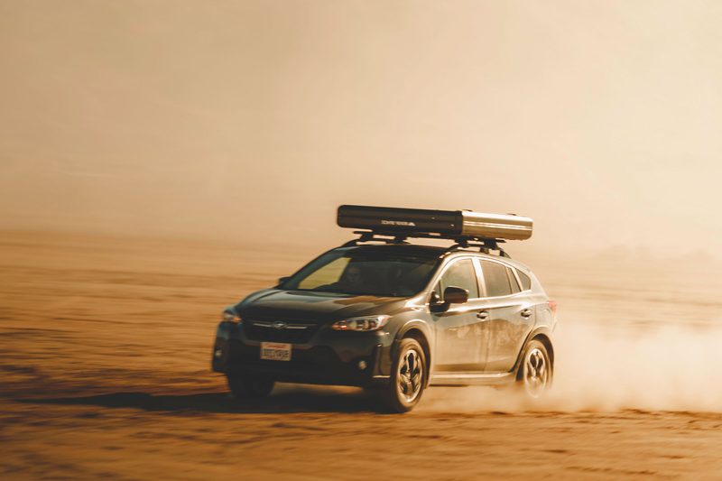 Roof Space 2 rooftop tent mounted on a small Subaru driving through the desert.