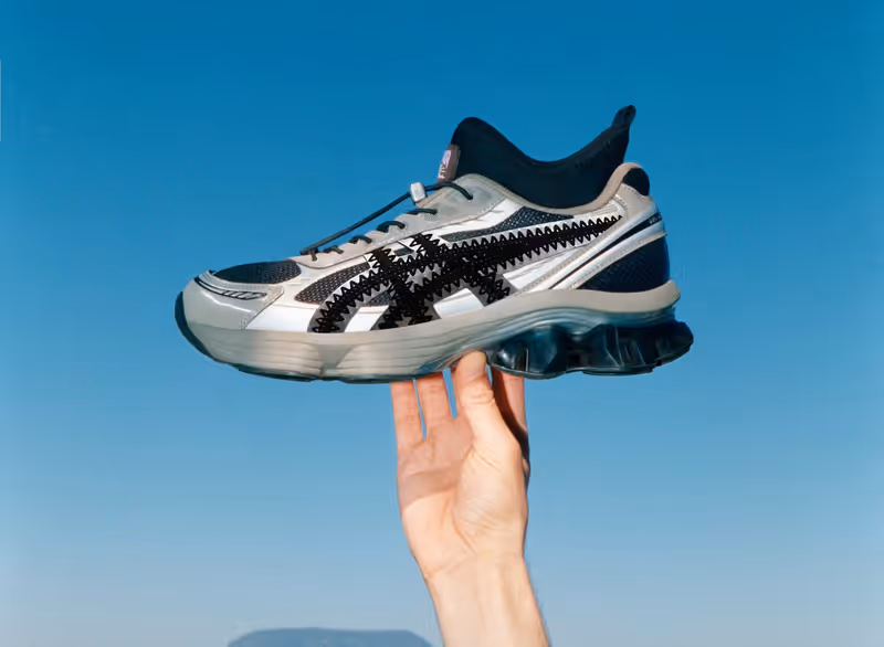hand holding silver and black asics sneaker