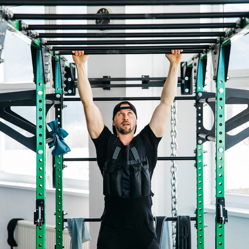 Man wearing weighted vest doing pull ups.