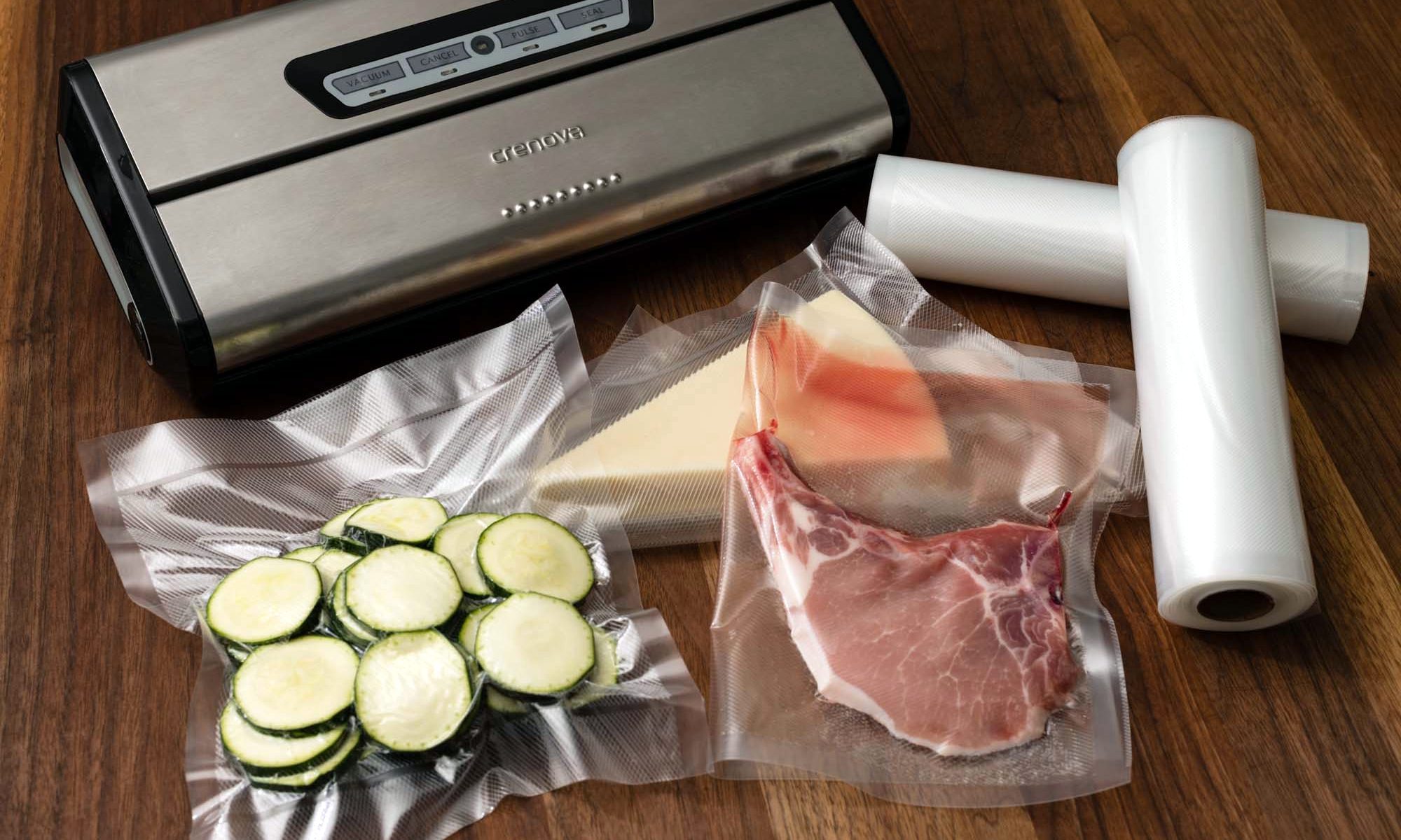 Cheese, zucchini, and a pork chop vacuum sealed in front of a vacuum seaker ona wooden table