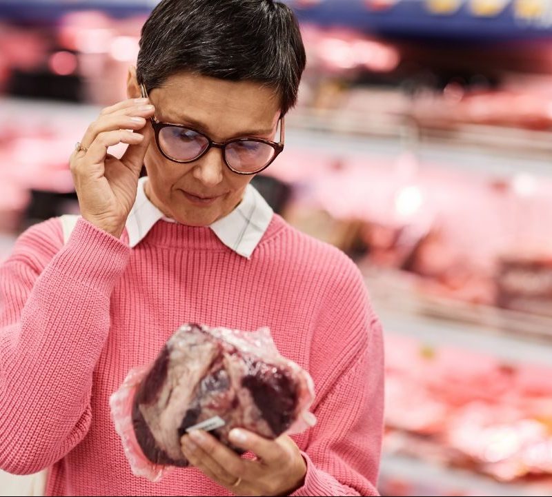 Woman adjusting her glasses and checking the date on a piece of meat