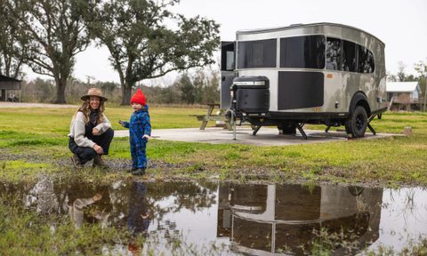 Young woman and a child camping near an Airstream 2025 Basecamp 20Xe travel trailer.