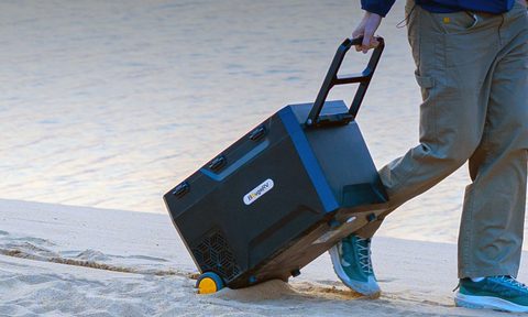 A BougeRV CRX2 battery-powered portable fridge being pulled across beach sand.