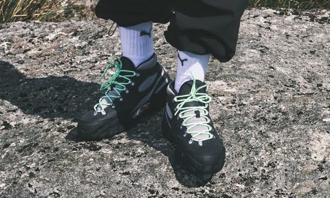 man wearing puma sneakers on rock