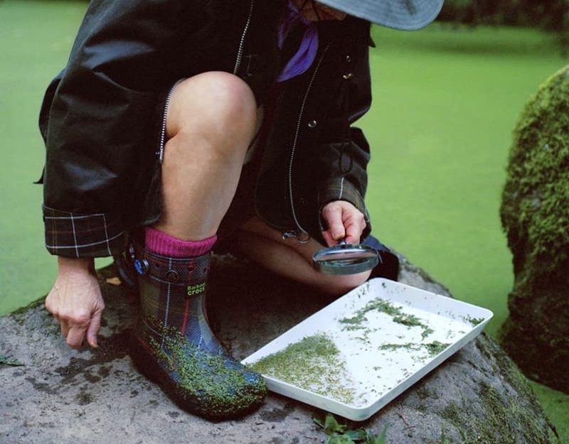 man in fisherman wear on rock with wellington boots