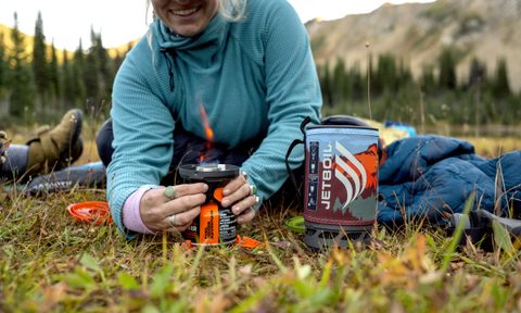 Woman cooking with a Jetboil Flash 1.0L Fast Boil system in a mountainous backcountry setting.