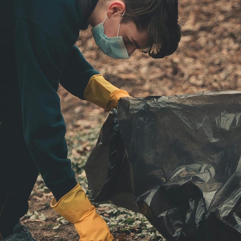 Man pliking picking up trash on hiking trail