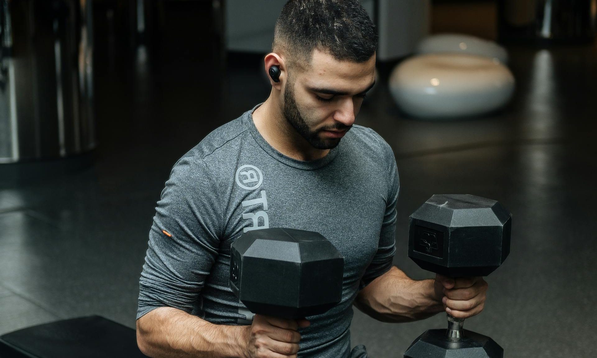 man holding two dumbbells on bench