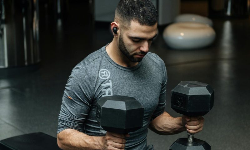 man holding two dumbbells on bench