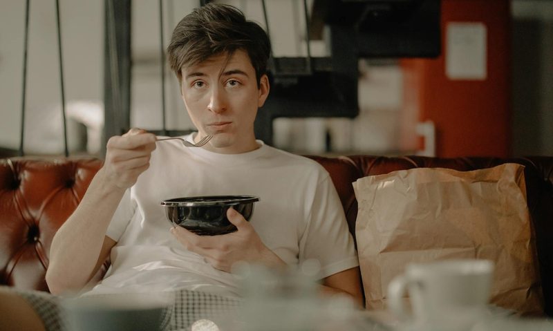 man eating food on couch
