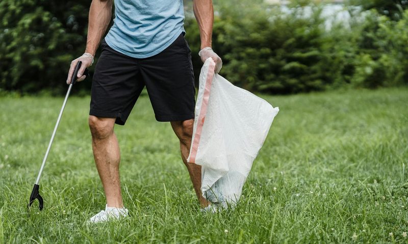 man picking up garbage with waste picker