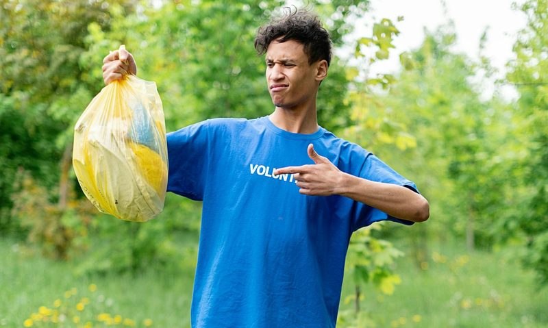 man holding trash bag in park