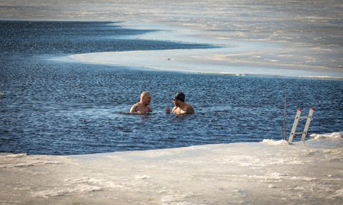 two men in icy lake ice bath swim