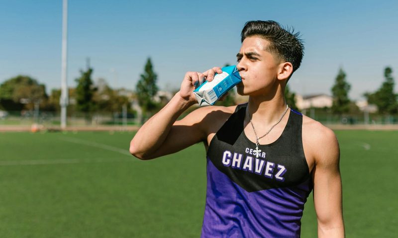 high school teenager on field drinking carton