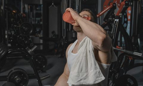 man sitting in gym drinking protein shake
