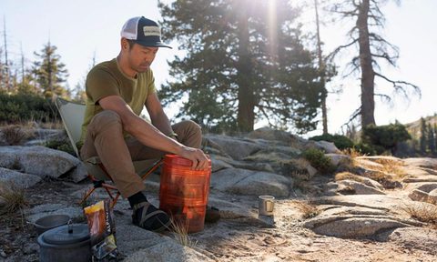 Man camping with an REI Traverse modular bear canister.