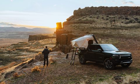 Rivian pickup truck with an iKamper Skycamp Mini rooftop tent parked near a desert overlook.
