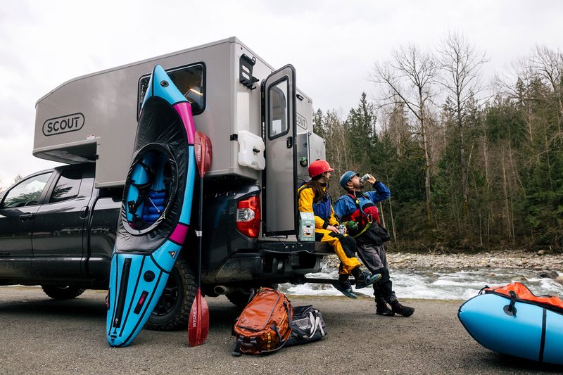 Young couple enjoying 10 Barrel Brewing's Camp Coldie IPA from the back of a Scout Campers truck camper.