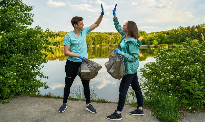 man and woman high five plogging trash bag