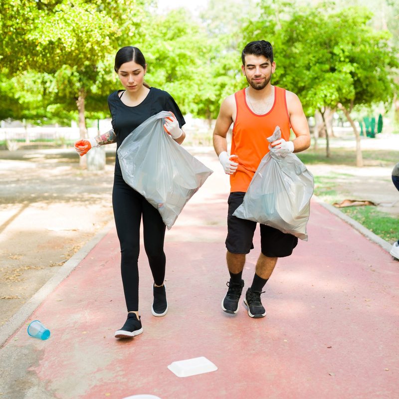 Man and woman plogging carrying trash bags