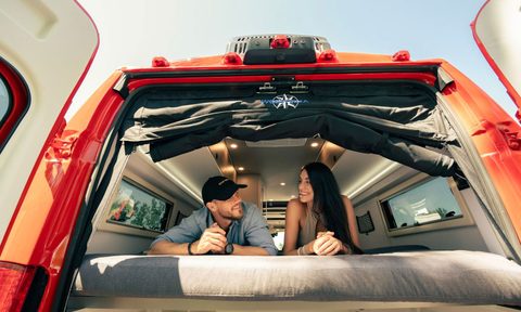 Young couple lying on the rear bed inside a Westfalia Wave SRT campervan.
