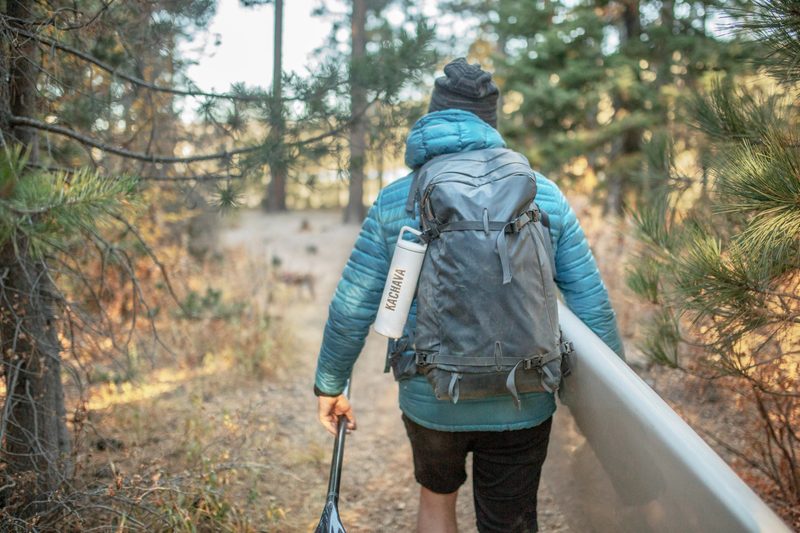 person hiking through the forest and carrying a Ka'chava bottle