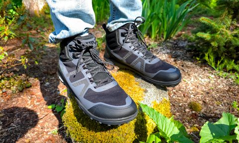 A man wearing Xero shoes while standing on a mossy rock