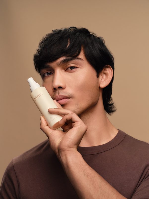 young man holding hair loss treatment spray