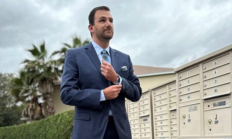 Man in blue shirt and suit fixing his collar