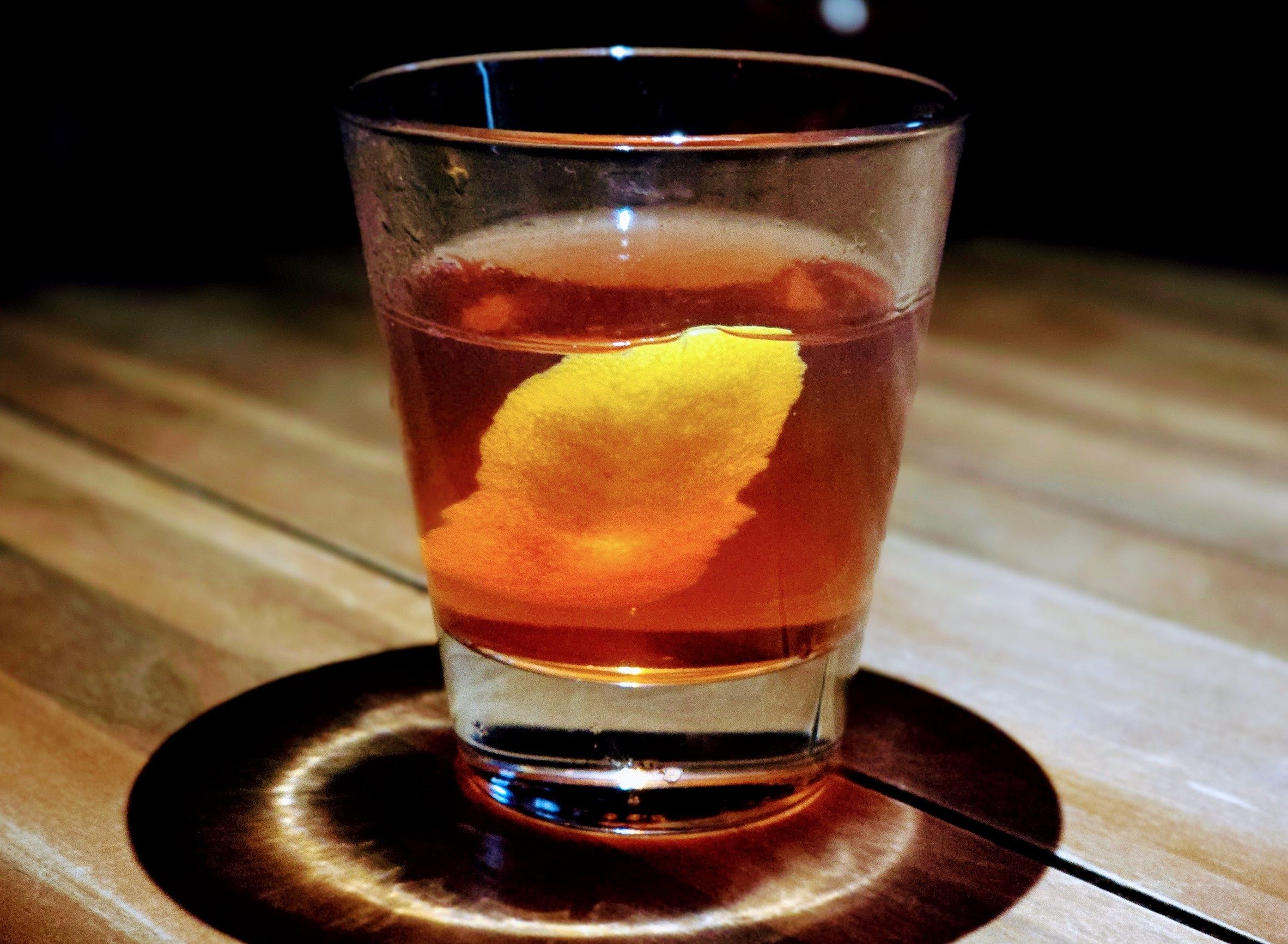 A glass with Sazerac on a dimly lit table