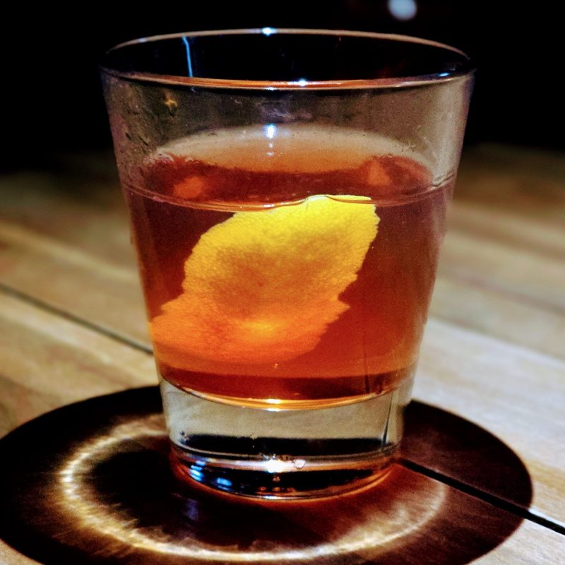 A glass with Sazerac on a dimly lit table
