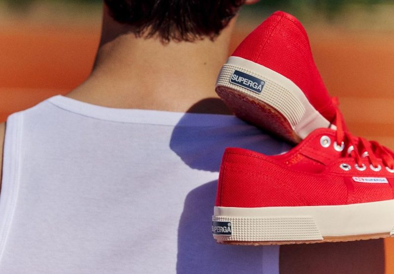 man hold red superga 2750 sneakers