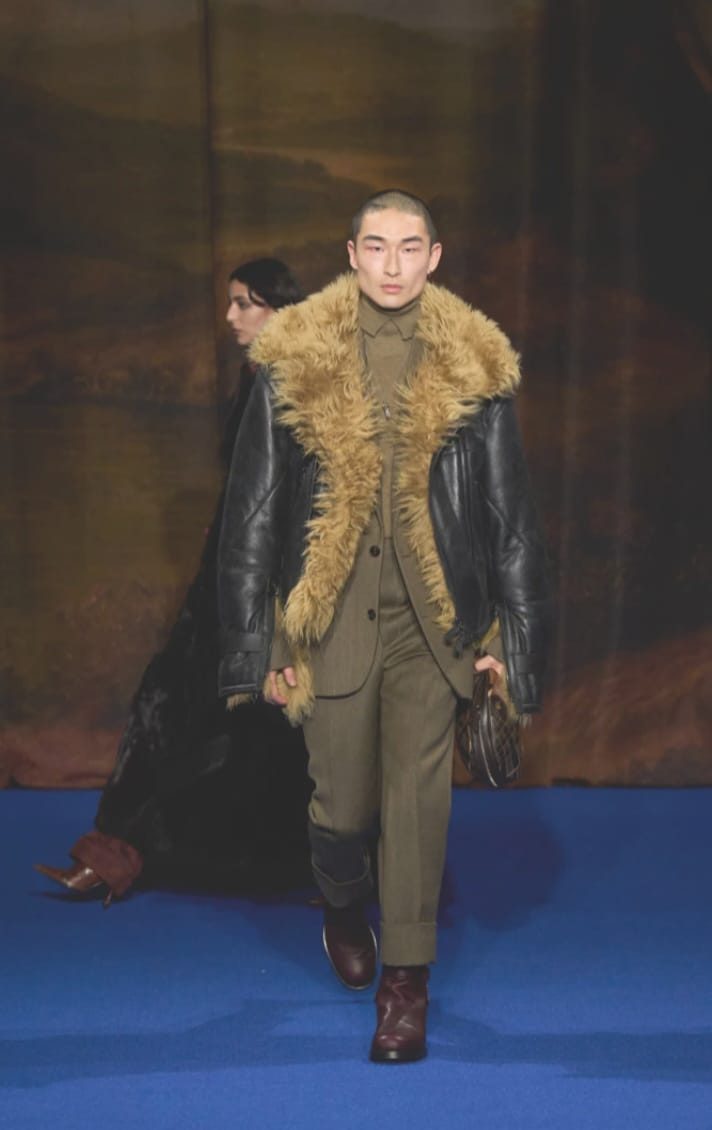 Model in black blazer with shearling collar and trim.