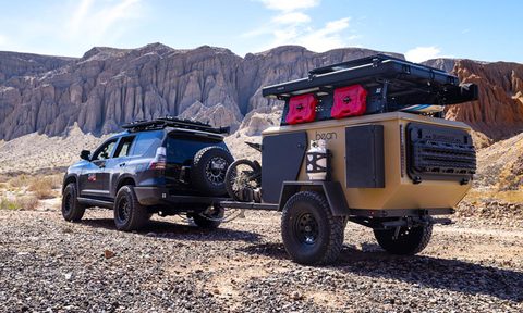 A Bean Pod adventure trailer being towed by a Toyota SUV through the desert.