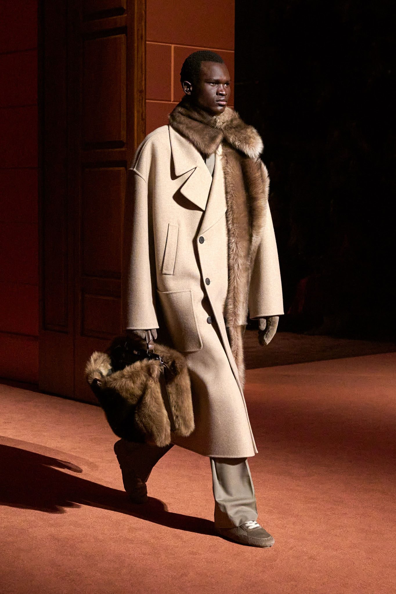 Model in long jacket with shearling accents with matchingshearling bag