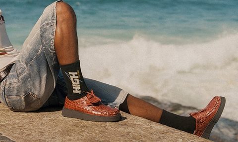 man laying on beach wearing martine rose clarks