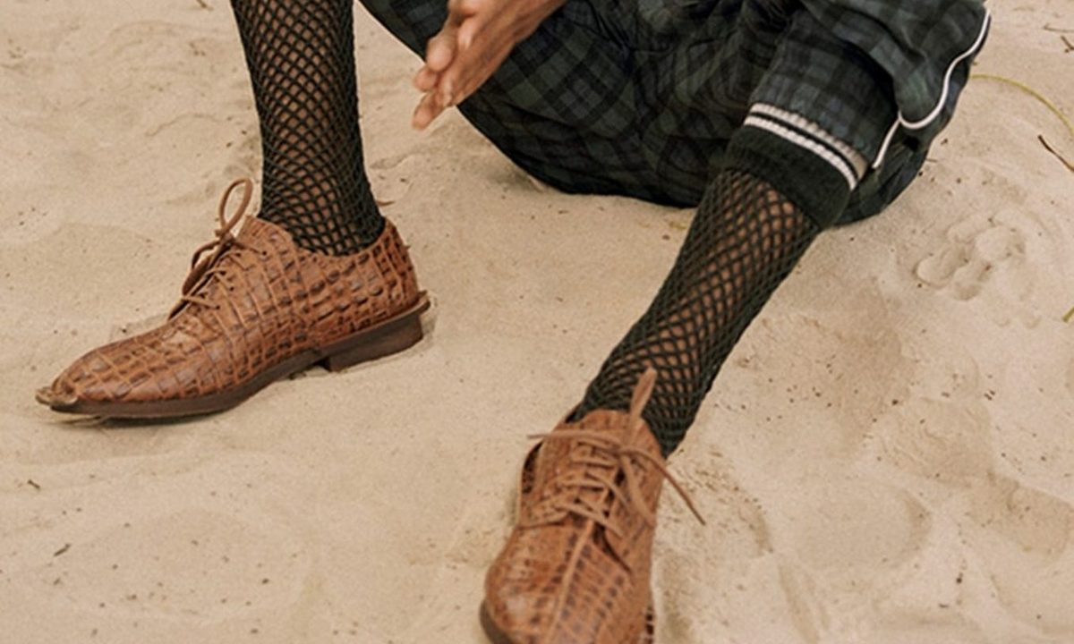 pair of brown croc shoes on beach