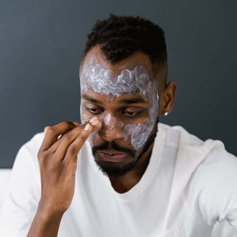 Man putting facial cream on face