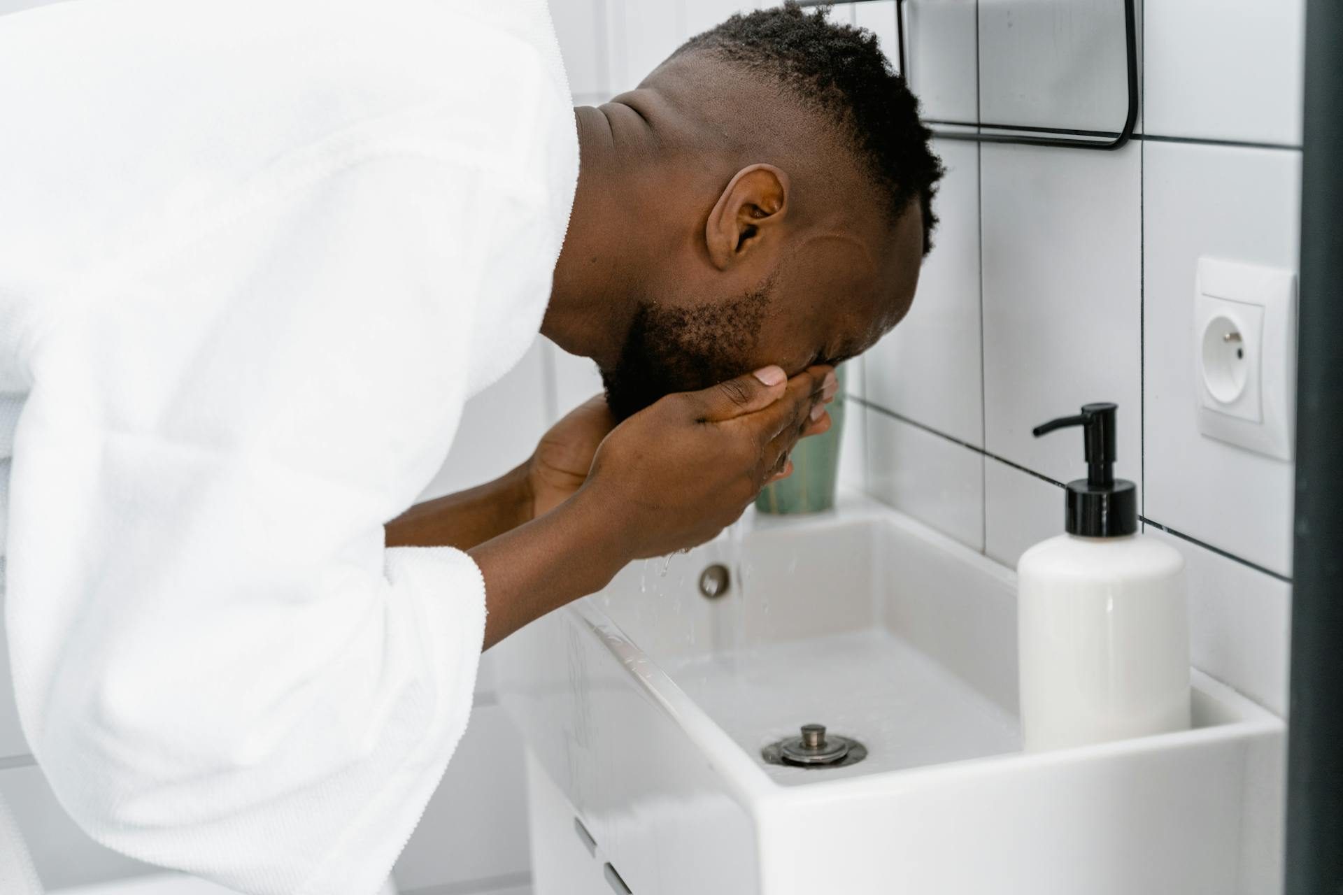 man washing face in bathroom