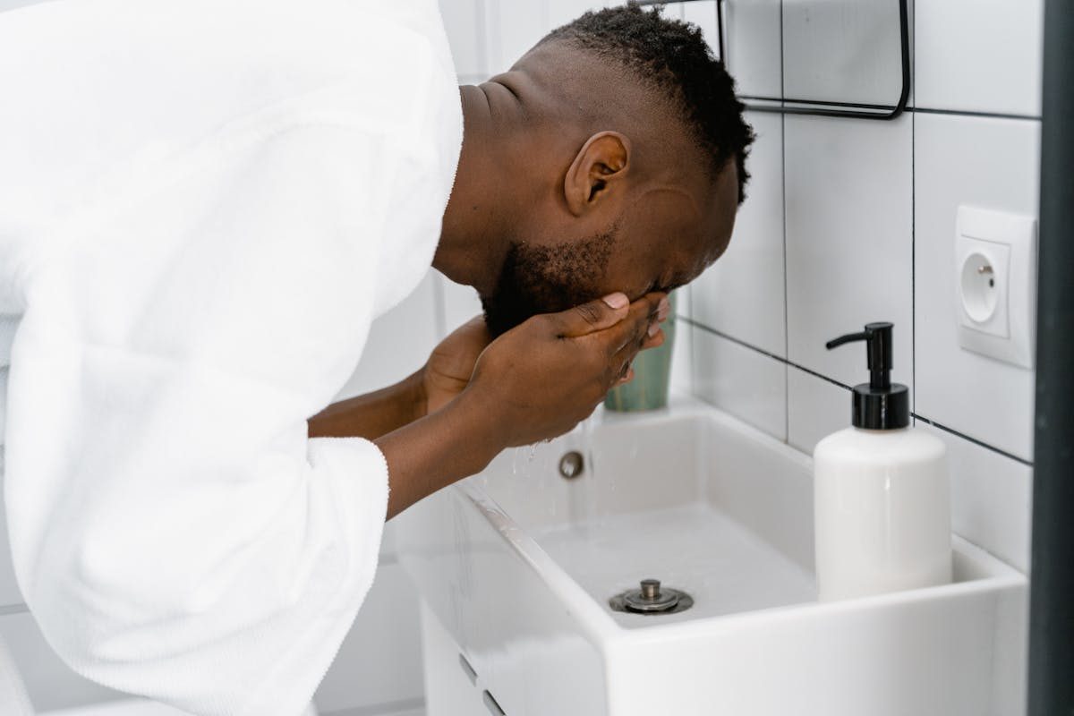 man in bathrobe washing face