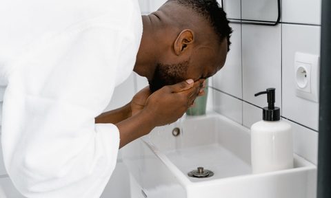 Man in a bathrobe washing his face