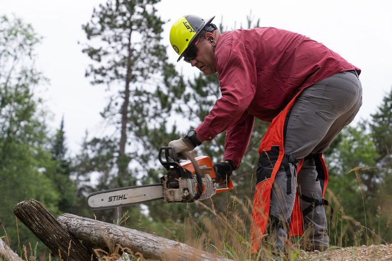 Man clearing a trail with a chainsaw during a past onX Trail Revival Project.